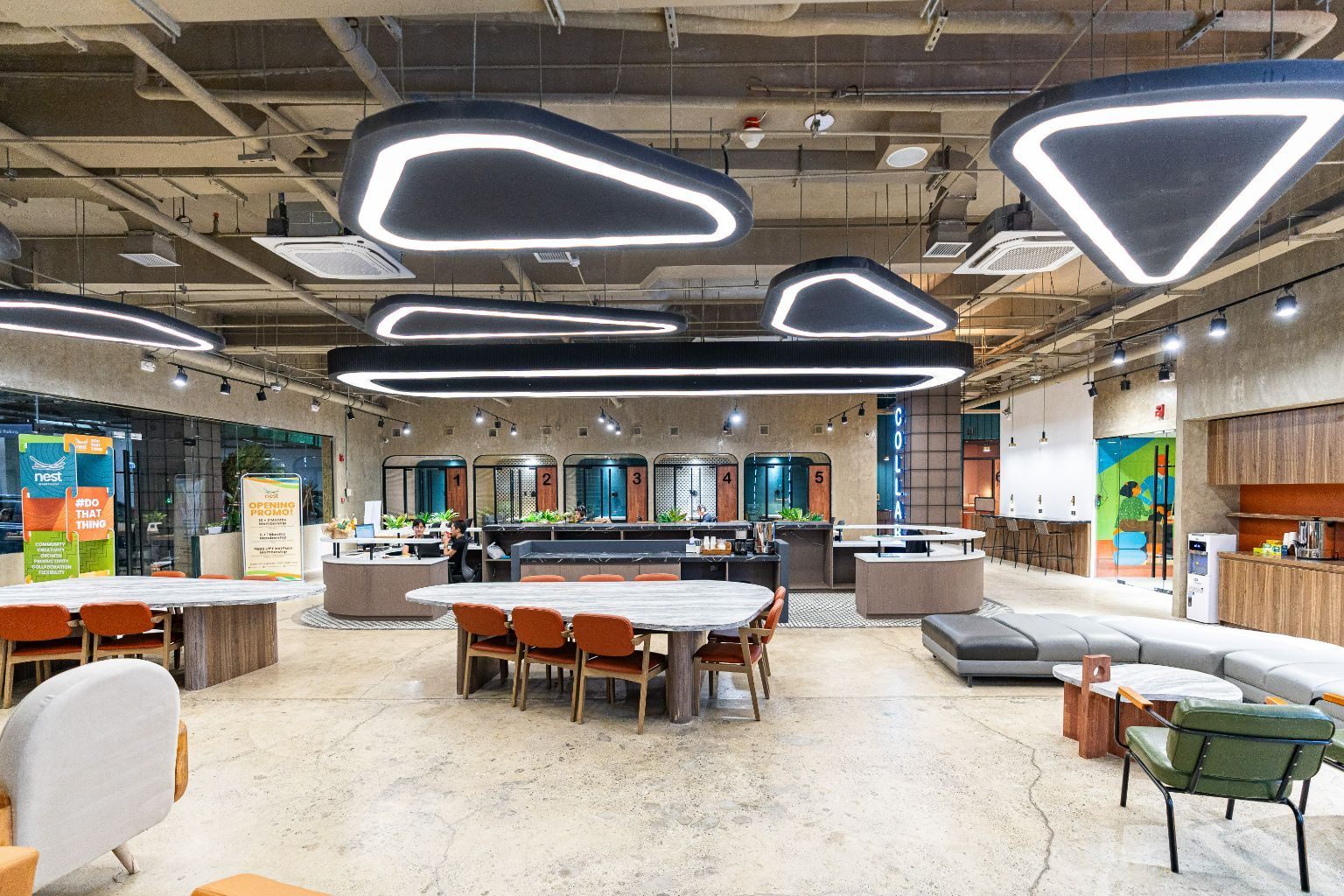 The Nest coworking floor, with marble tables, orange chairs and the front desk under loop pendant lights